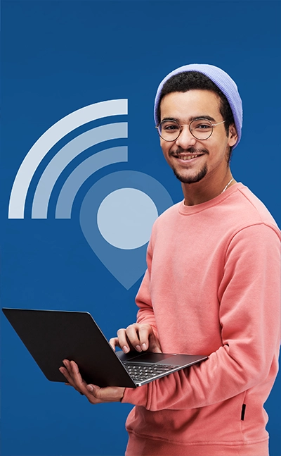 Junger Mann mit Laptop und WLAN-Symbol im Hintergrund – Symbolbild für das mobile Arbeiten mit einer Online-Lösung