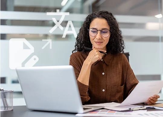 Frau am Schreibtisch mit einem Laptop und stilisierten Schriftzeichen im Hintergrund – symbolisch für unseren Übersetzungsservice