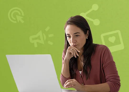 Frau sitzt nachdenklich vor Laptop, hinter ihr ein grüner Hintergrund