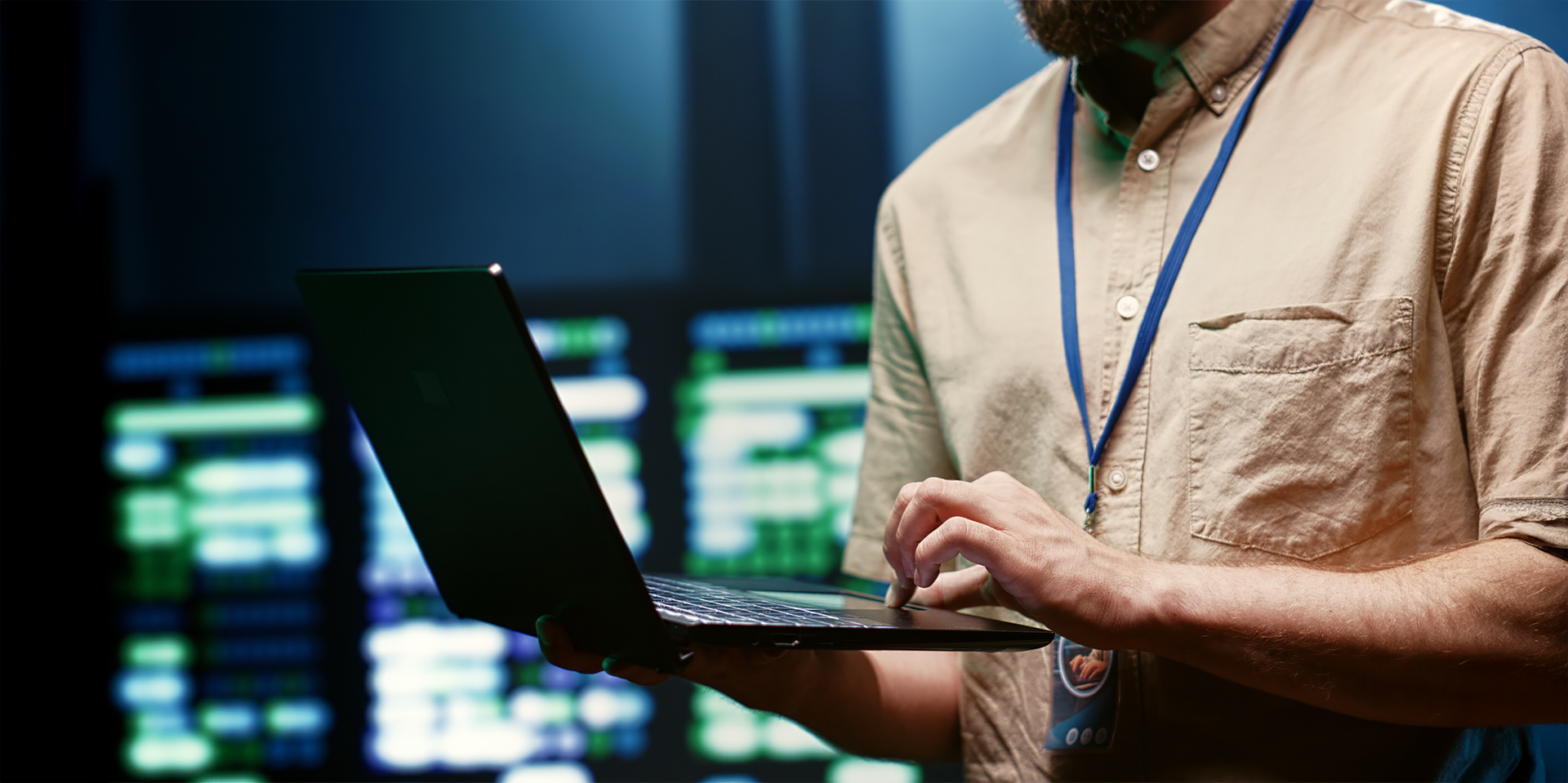 Ein Mann mit Bart hält einen Laptop in der Hand.